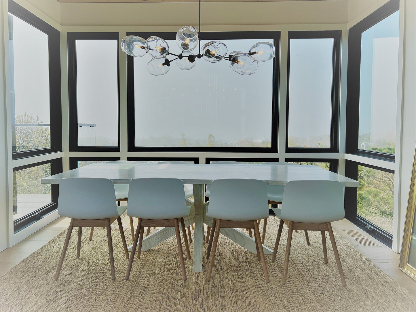Contemporary Petra Santina chandelier featured over a modern dining table with glass diffusers and stylish chairs.