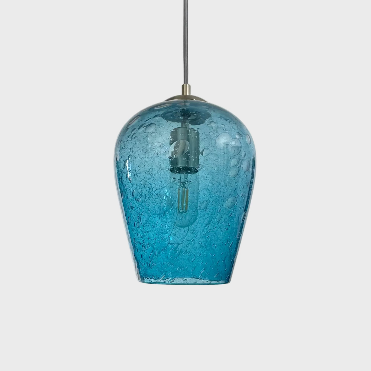 Aqua blue bubble glass pendant light with brushed nickel hardware and silver cord on a white background