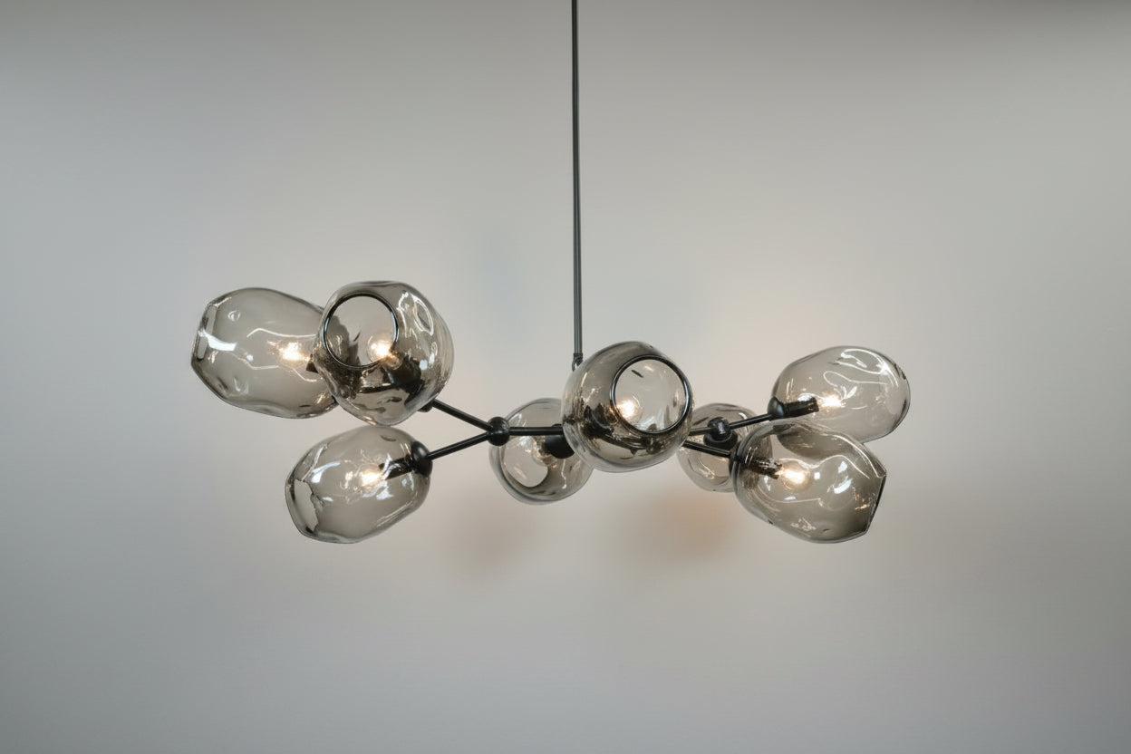A branching chandelier with 8 grey glass shades and a black chandelier frame. 