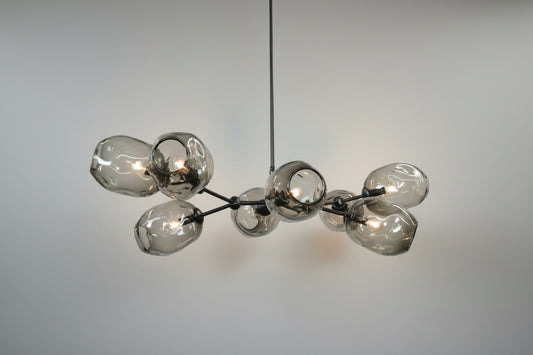 A branching chandelier with 8 grey glass shades and a black chandelier frame. 