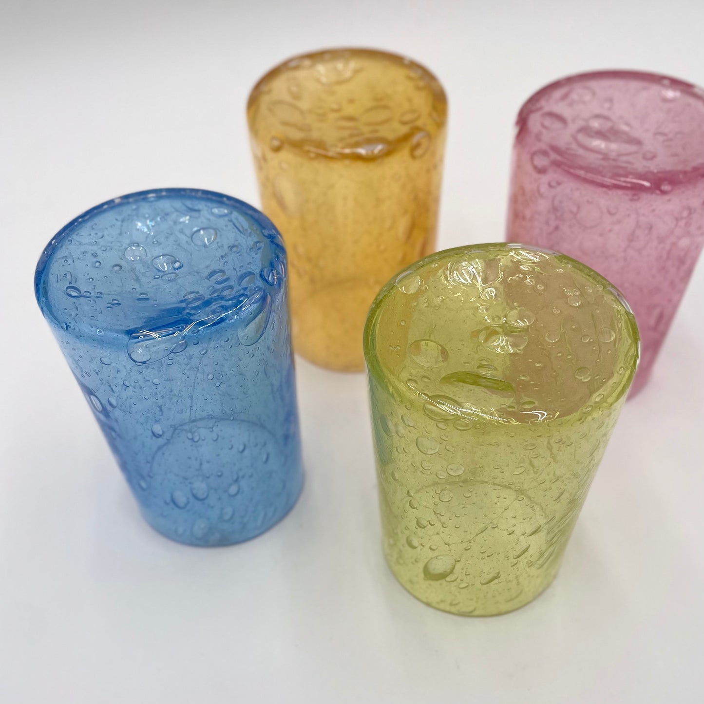 four colorful glass tumblers placed upside-down on a white background