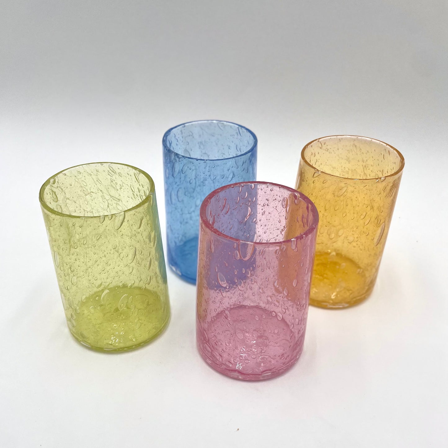Four colorful textured glass tumblers on a white background